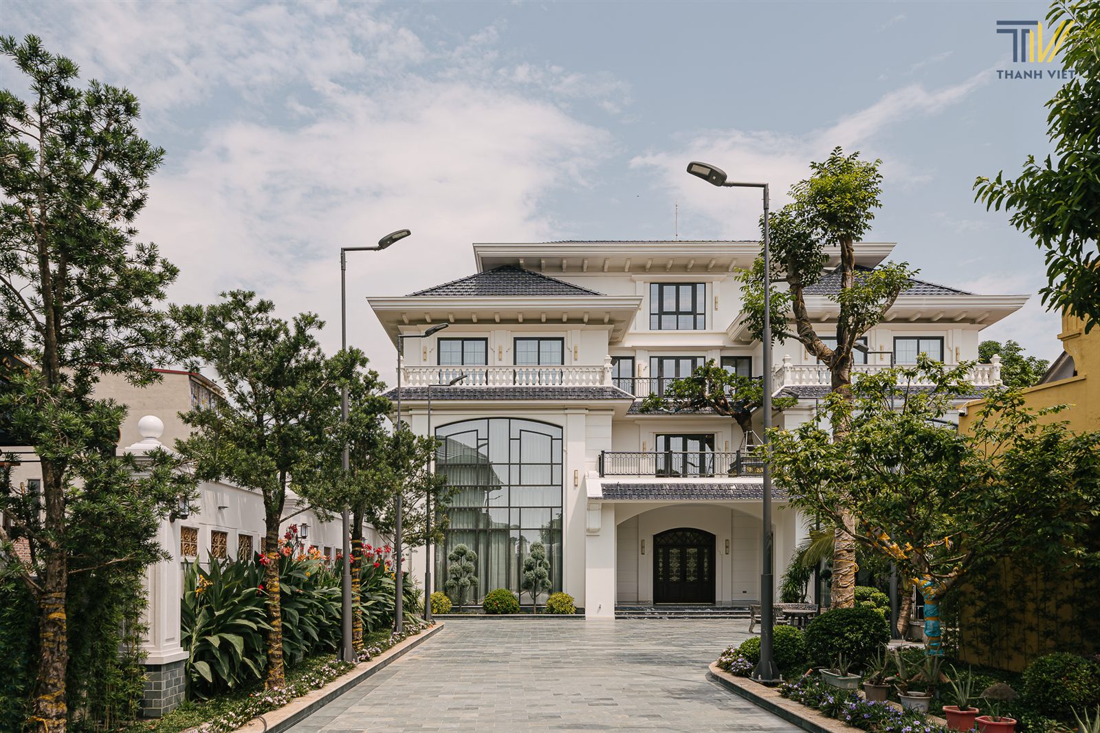 Mặt ngoài biệt thự Maison Villa, tông trắng, sân lát đá và cây xanh